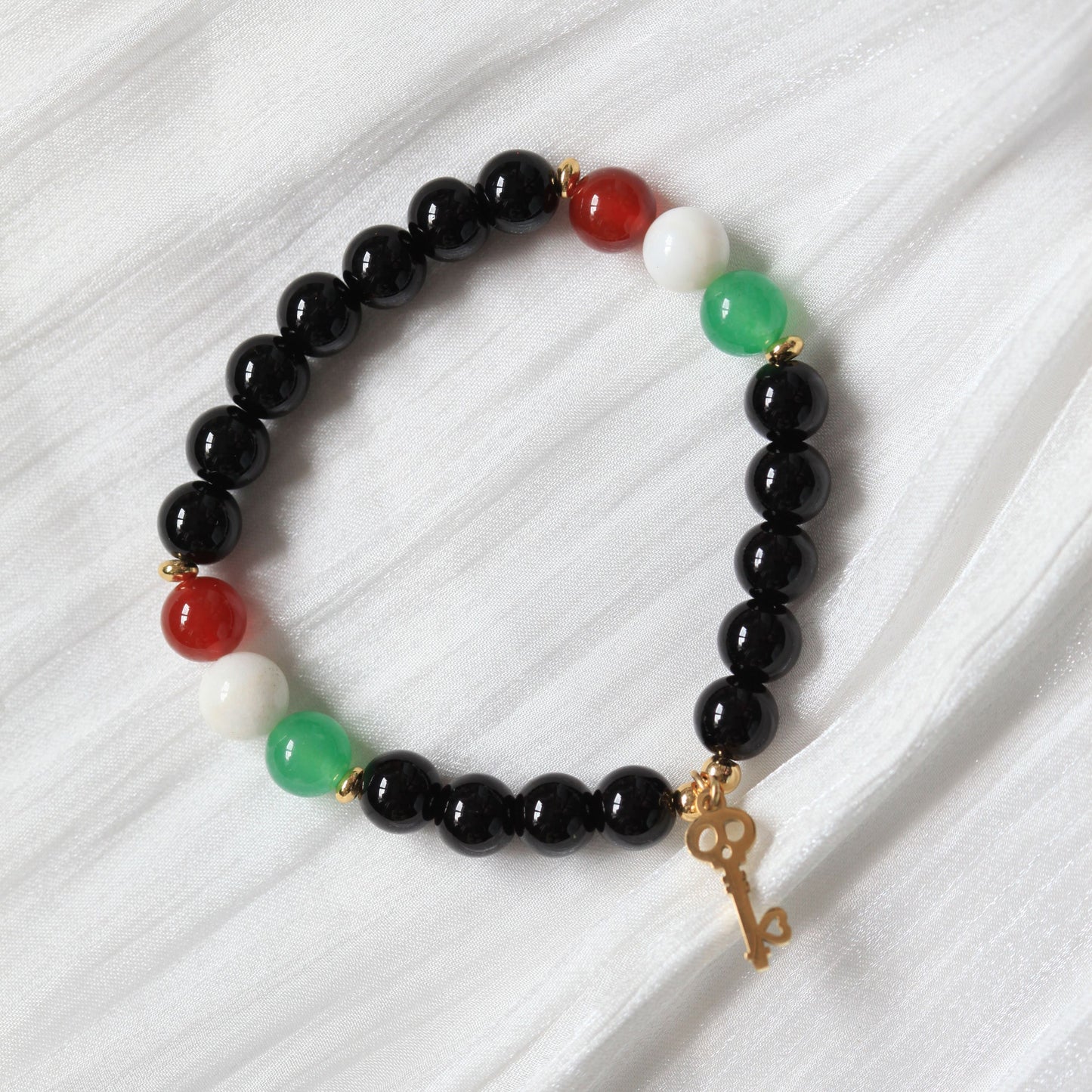 Bracelet with black, red, and green beads on a white background