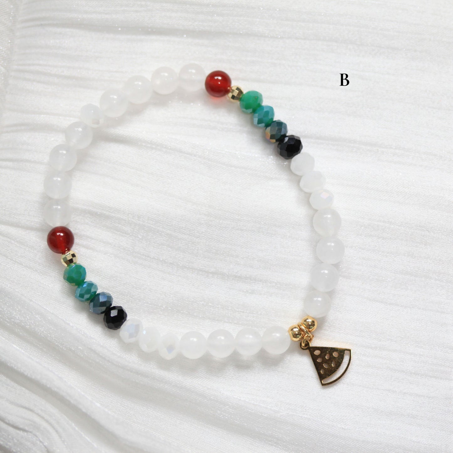 Tasbih Bracelet with colorful beads and a watermelon small charm on a white fabric background