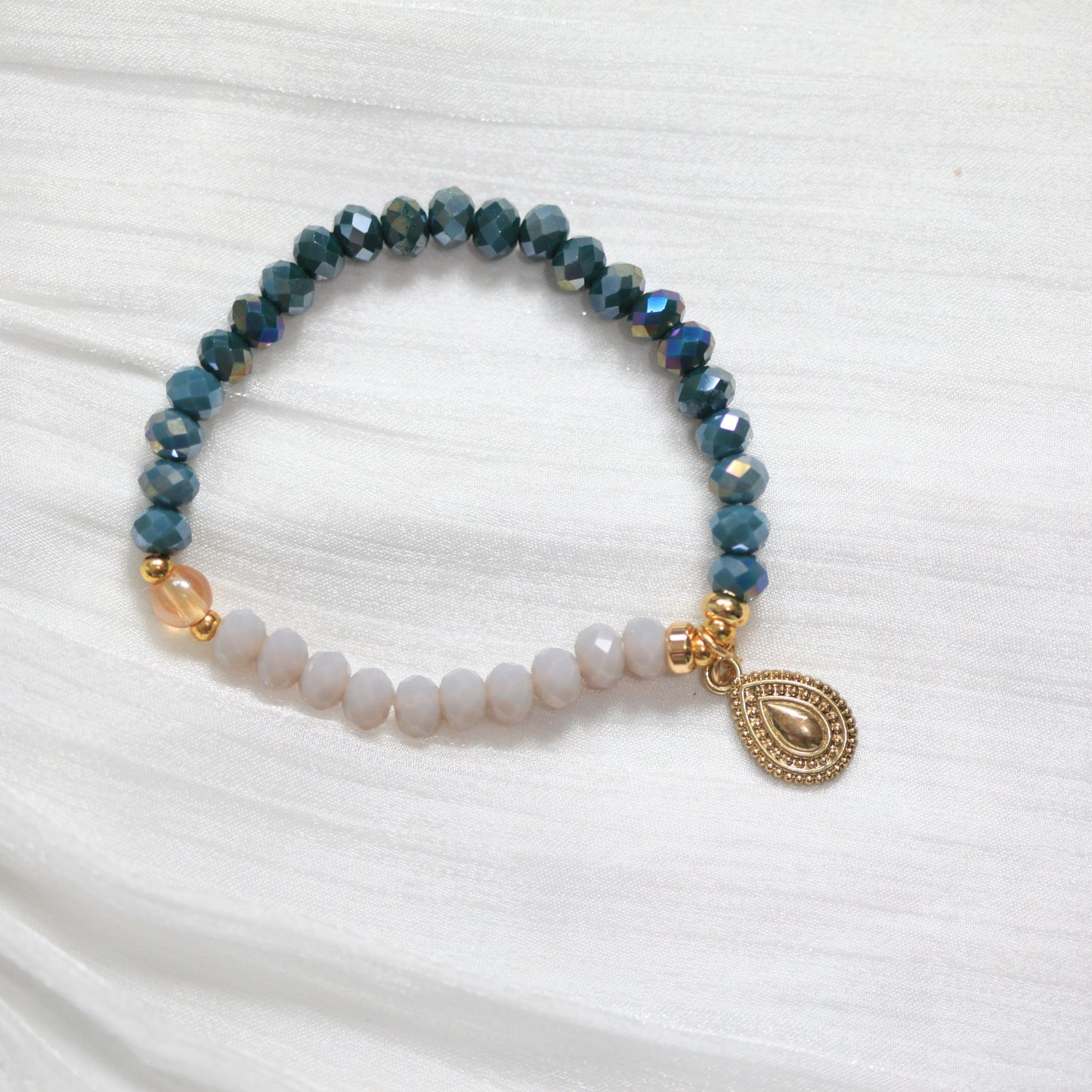 Tasbih Beaded bracelet with a gold charm on a white fabric background