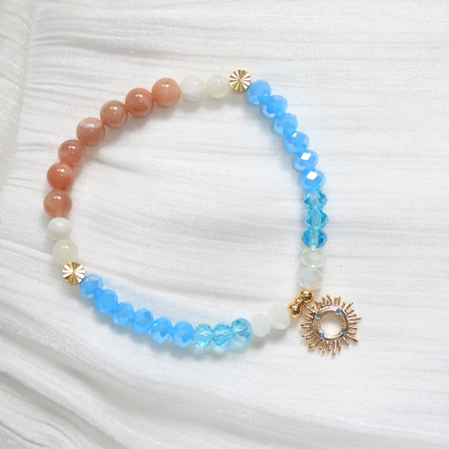 Beaded bracelet with blue, white, and gold accents on a white fabric background