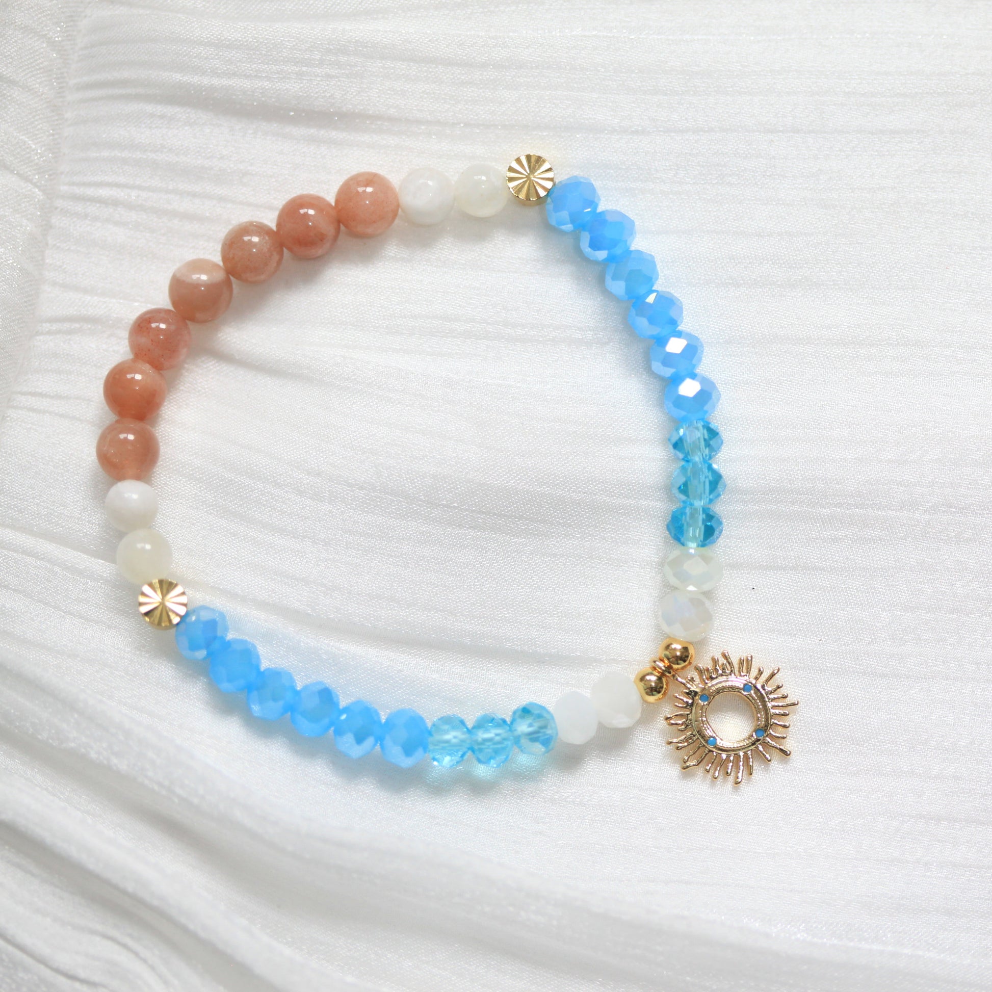 Beaded bracelet with blue, white, and gold accents on a white fabric background