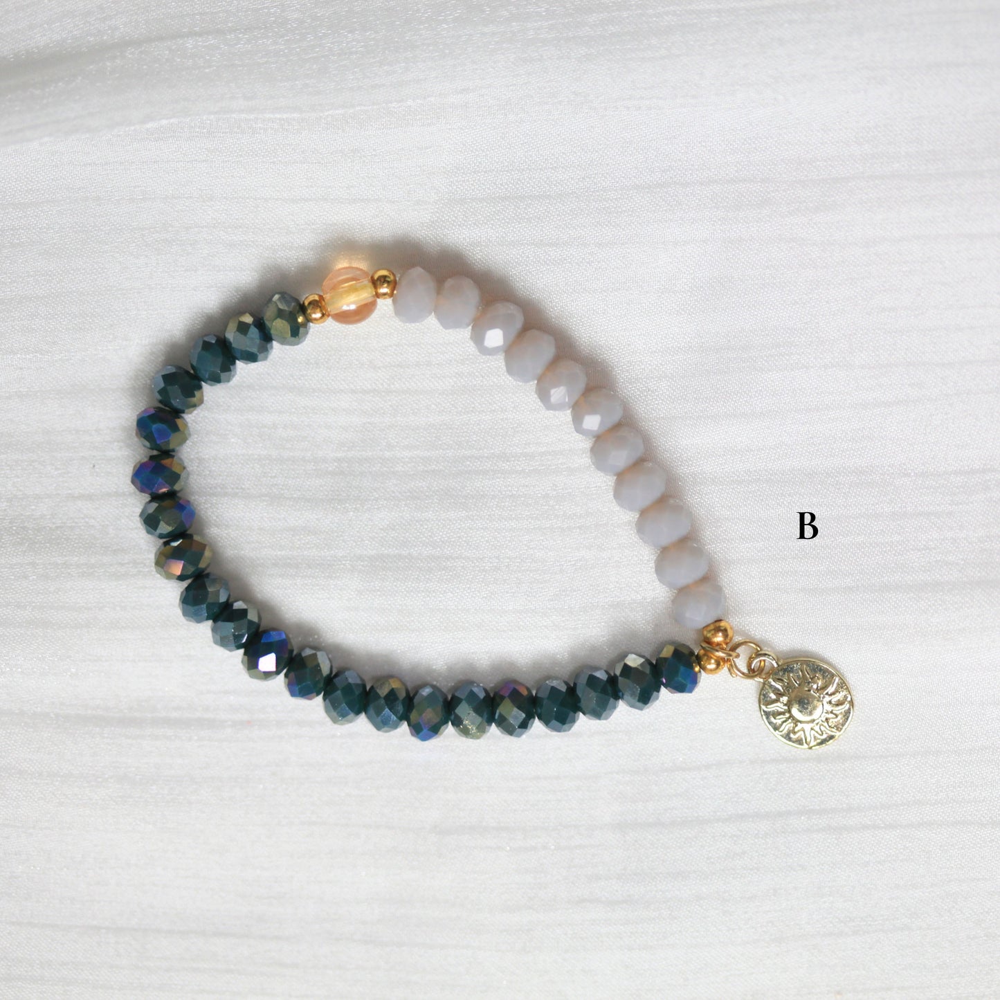 Beaded bracelet with a gold charm on a white background