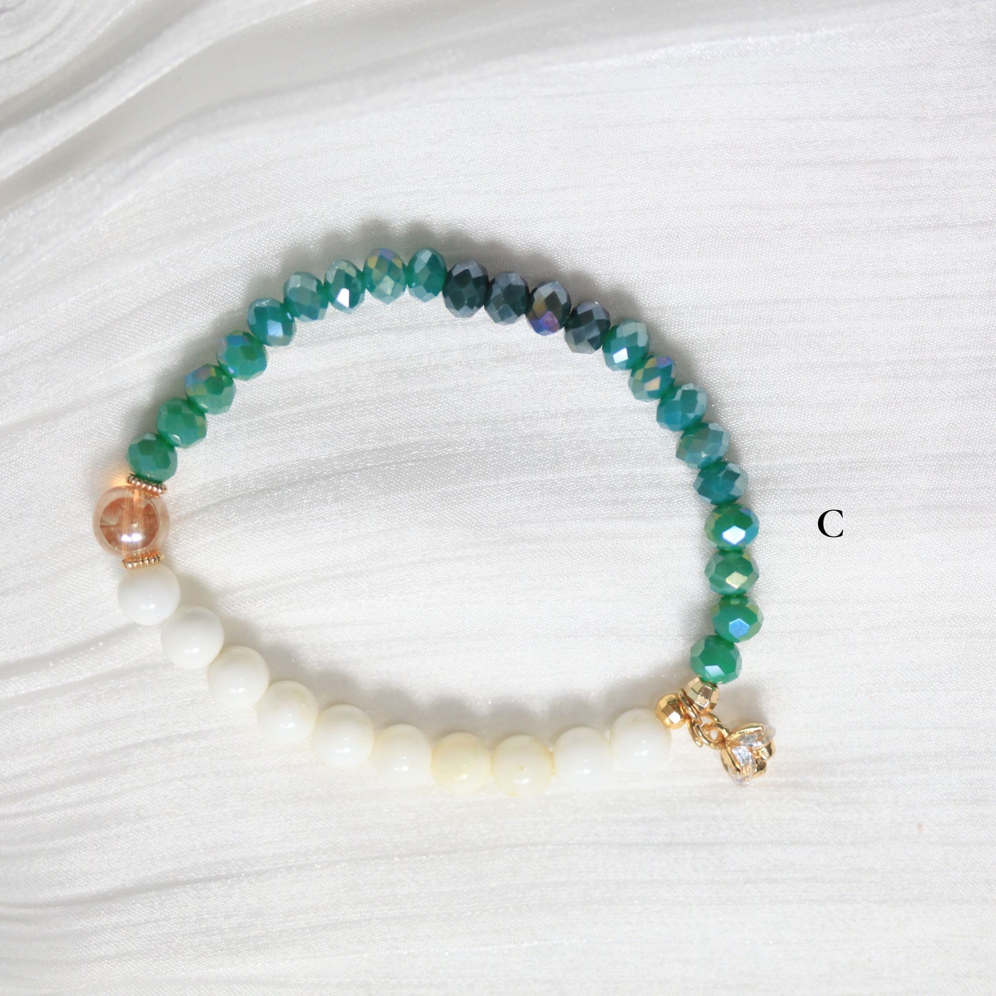 Beaded bracelet with green and white beads on a white fabric background