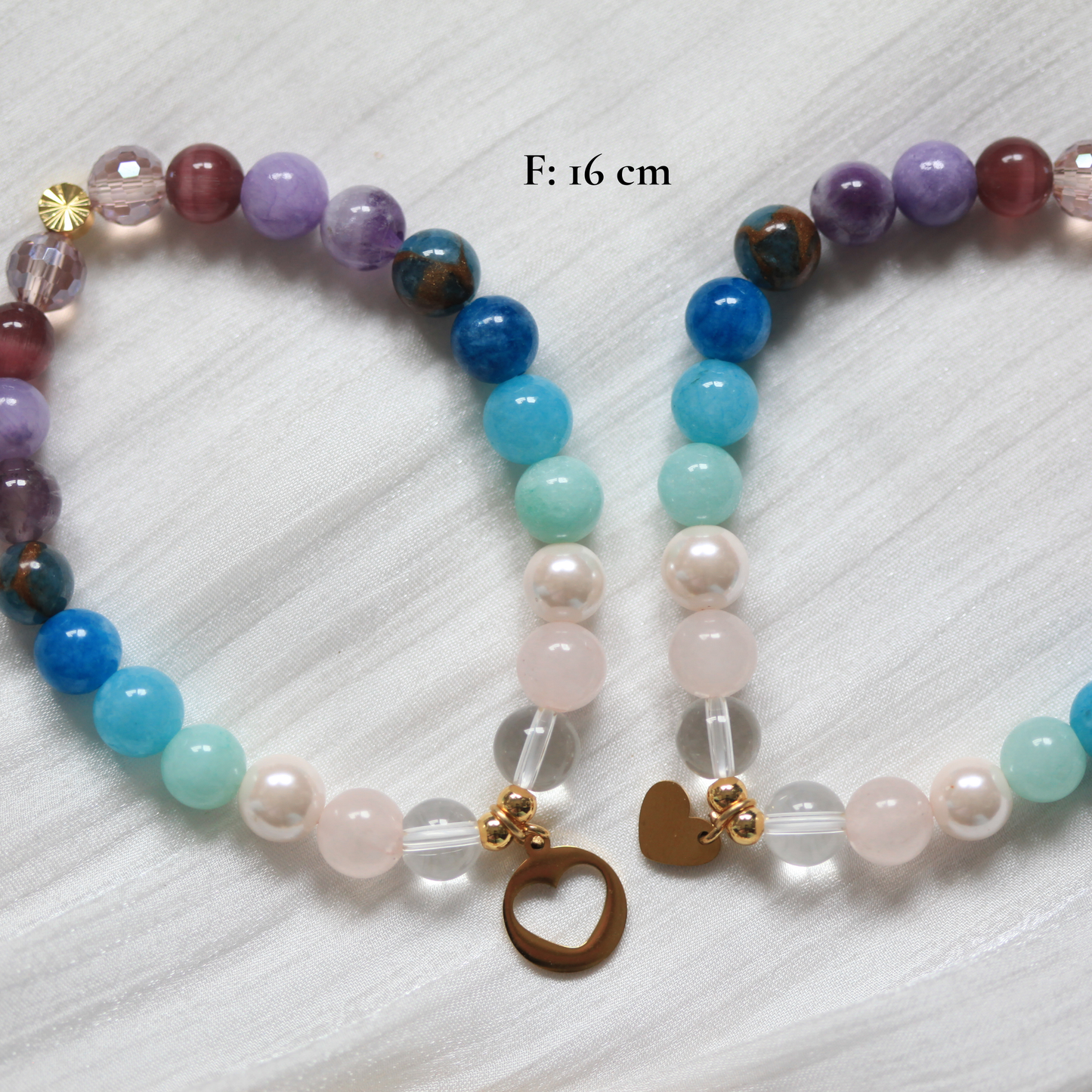 Multicolored beaded bracelet with heart charm on a textured white background