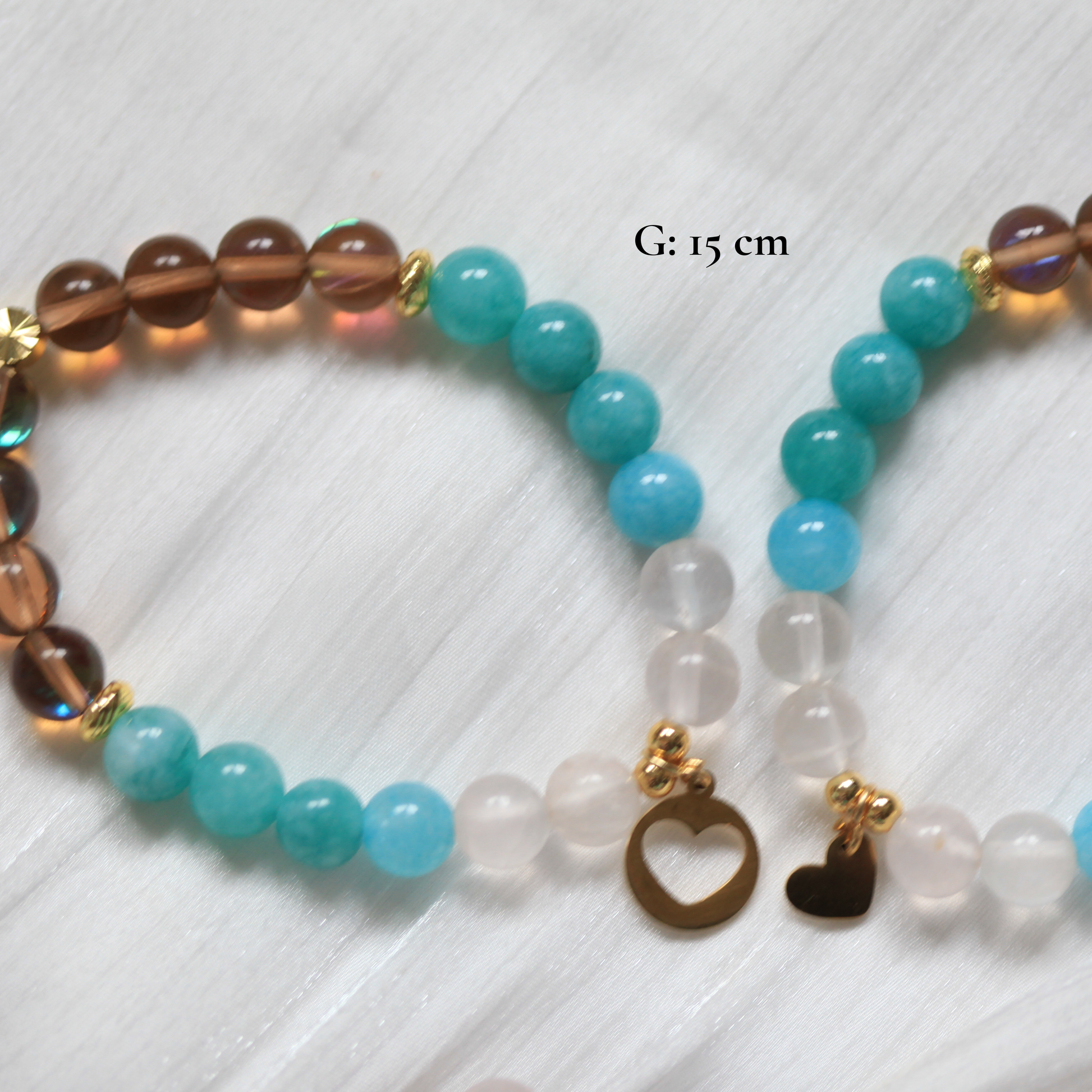 Beaded matching friendship bracelet with heart charms on a white textured background