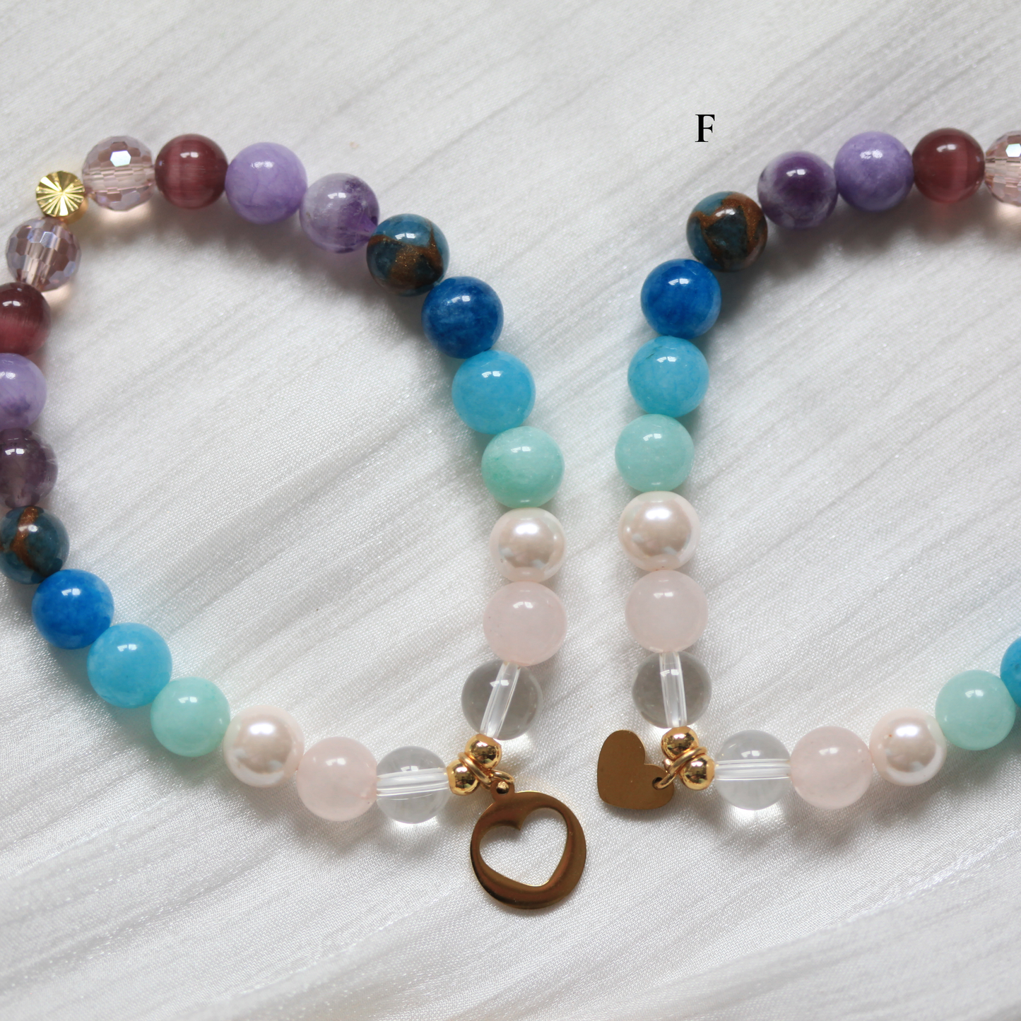 Colorful matching beaded bracelets with heart-shaped charms on a textured white surface.  Made by Dreamersside