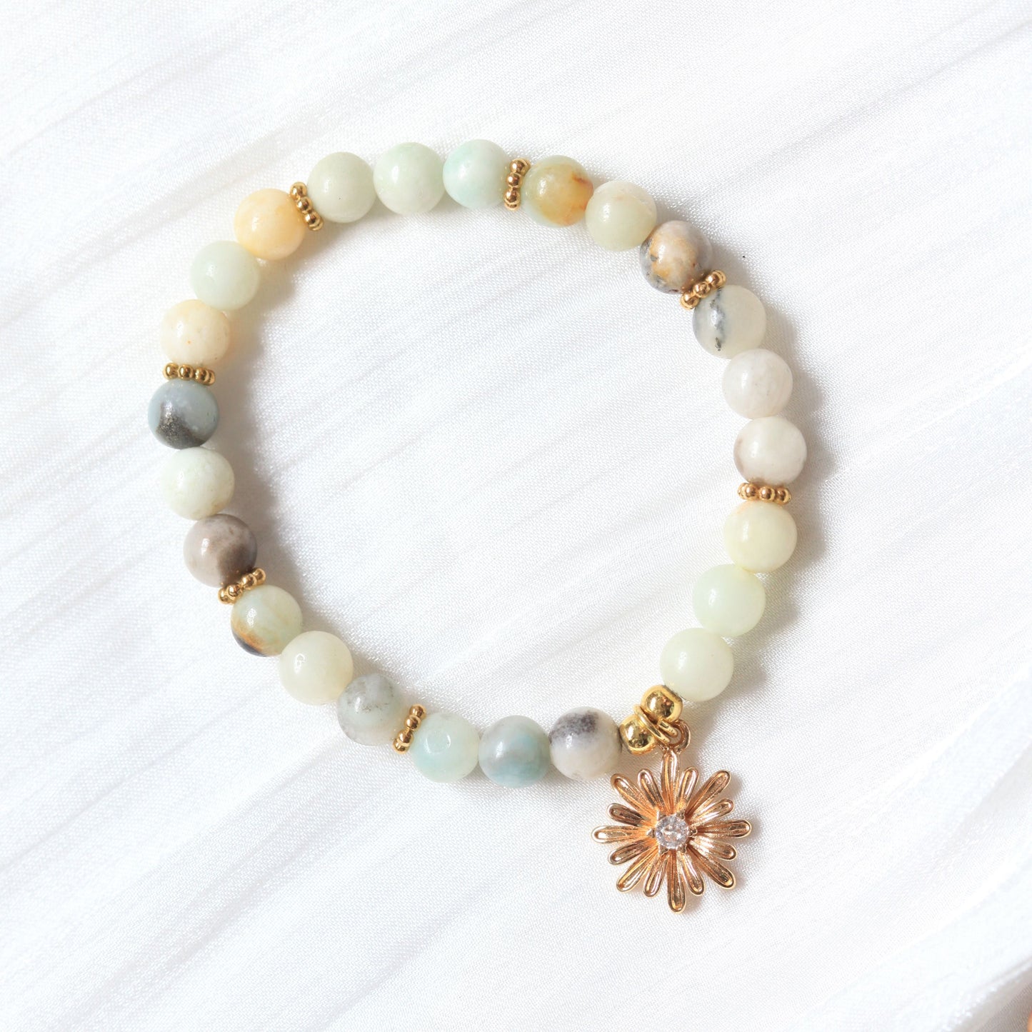 Beaded bracelet with a gold flower charm on a white background