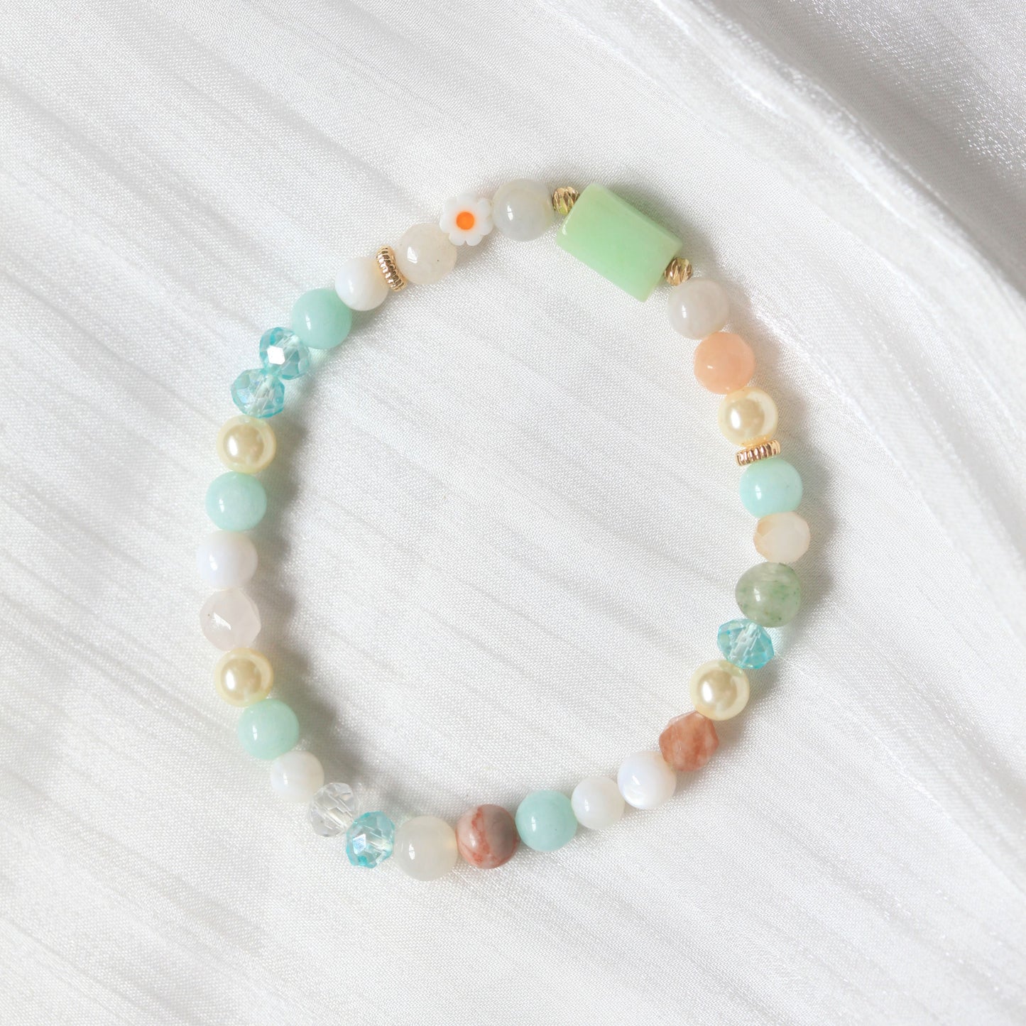 Beaded bracelet with pastel colors on a white fabric background