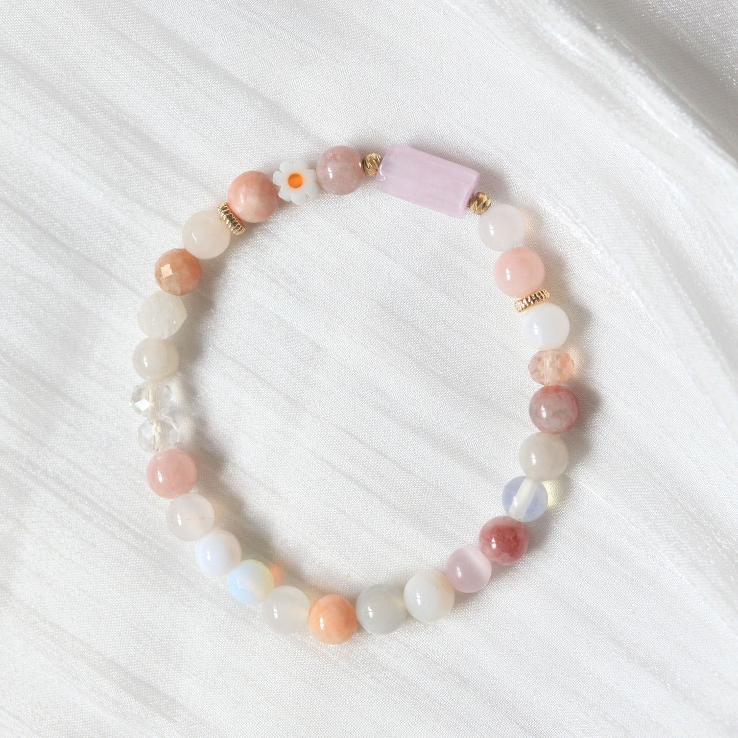Beaded bracelet with pastel-colored beads on a white textured surface
