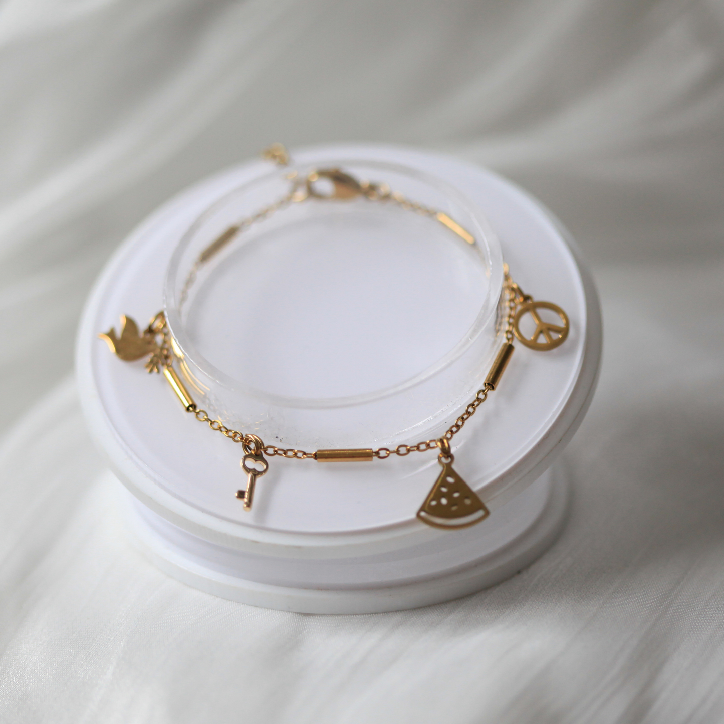 Gold bracelets with various charms on a white stand