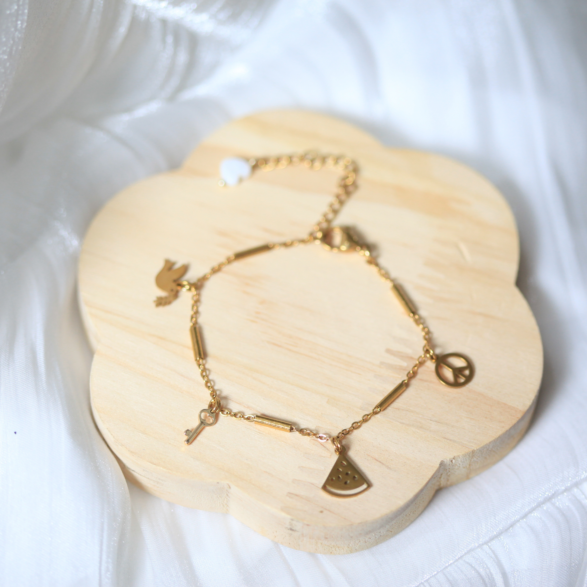 Gold bracelet with charms on a wooden coaster