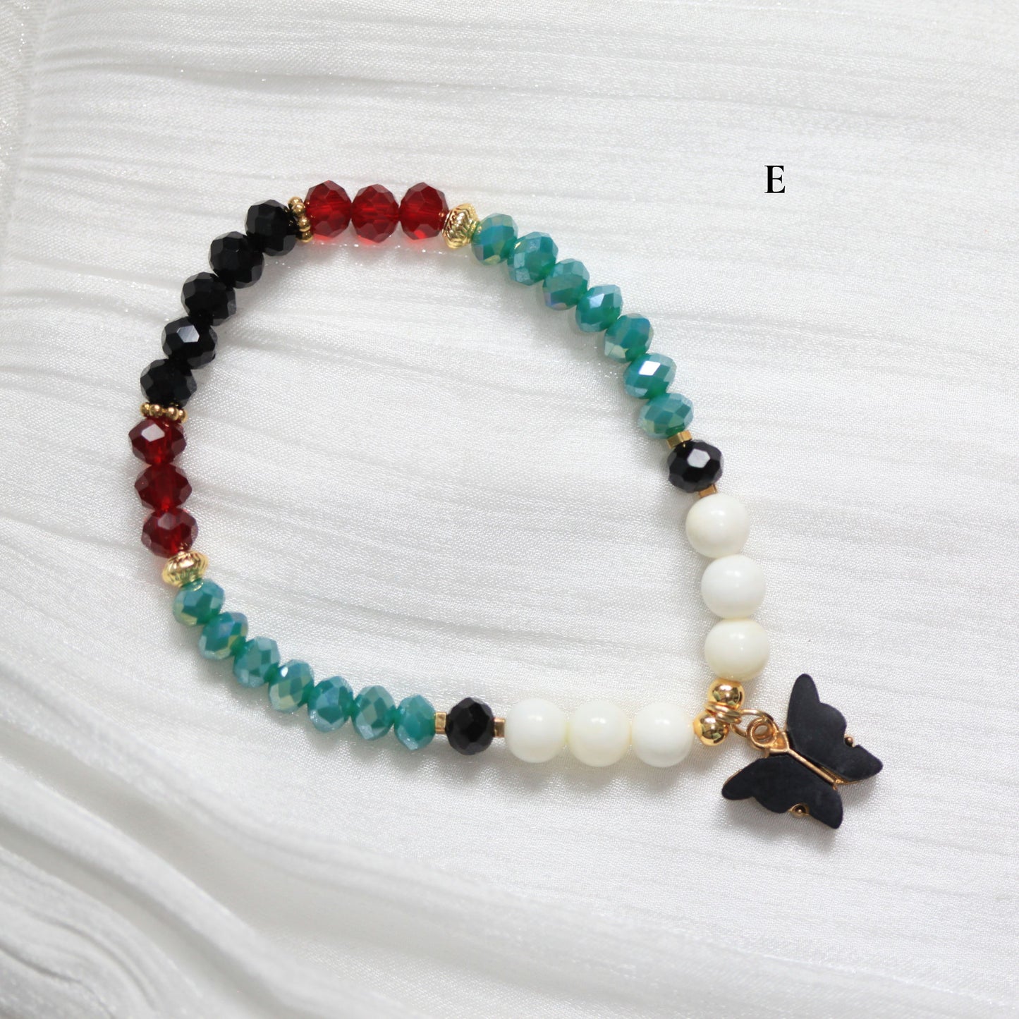 Tasbih Beaded bracelet with a butterfly charm on a white fabric background