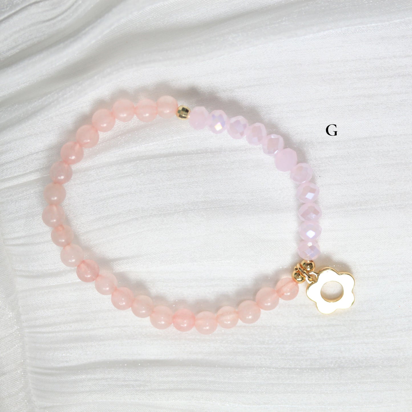 Pink beaded tasbih bracelet with a gold flower on a white background