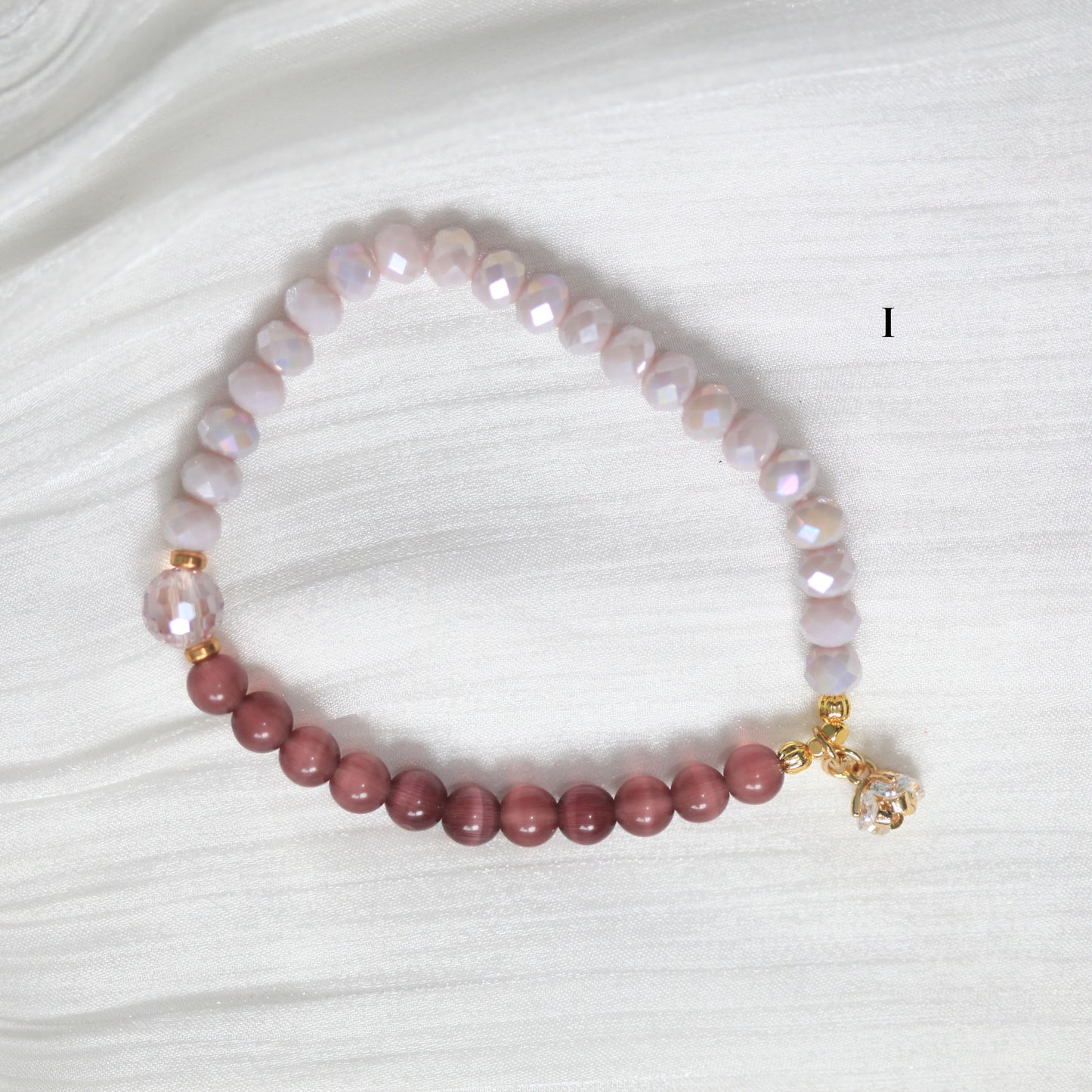 Beaded bracelet with pink and white beads on a white fabric background