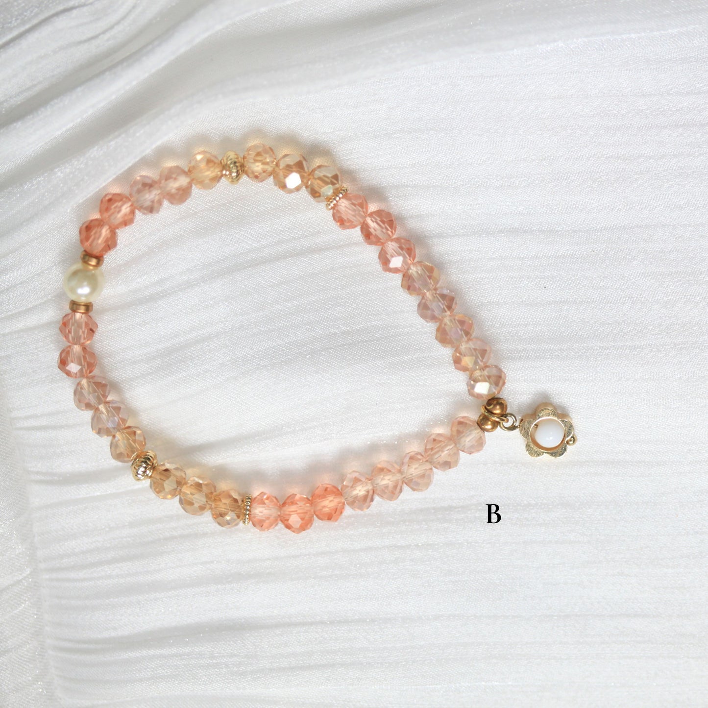 Tasbih Beaded bracelet with pink and gold accents on a white fabric background