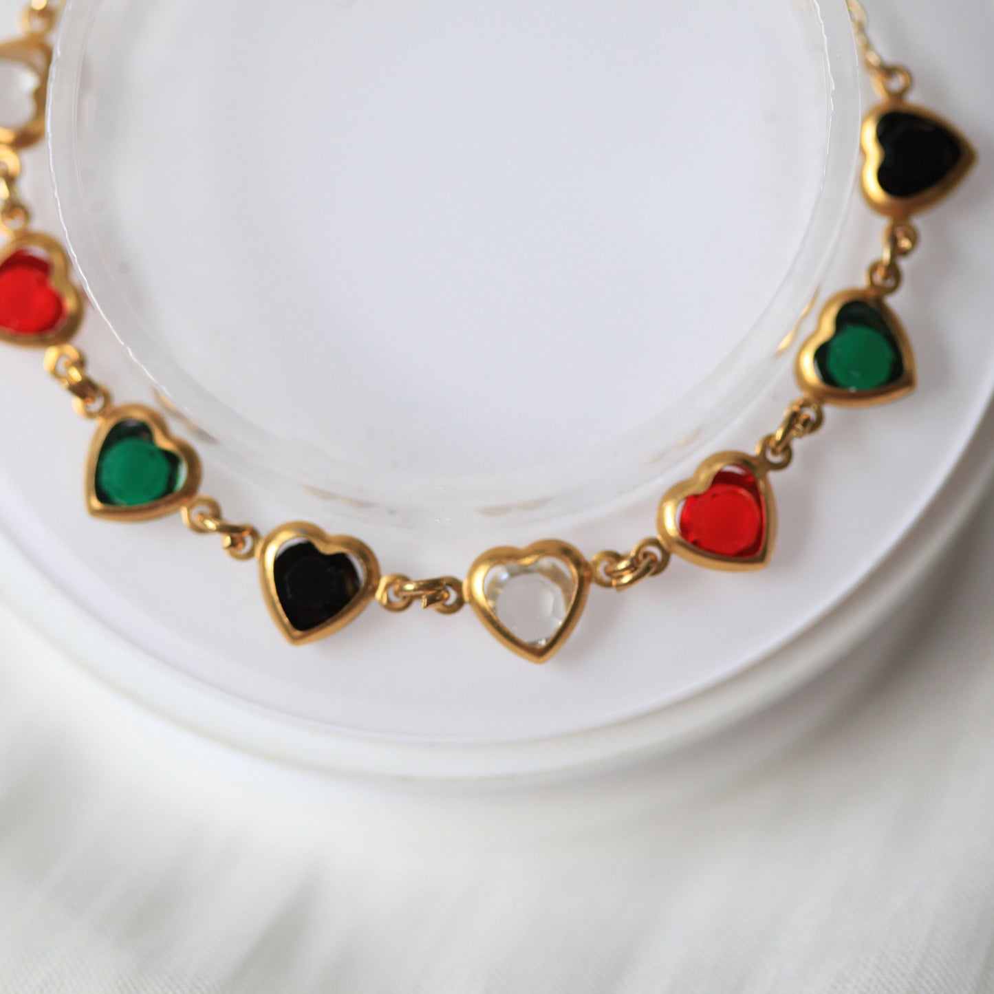 Bracelet with heart-shaped pendants in red, green, and clear on a white background