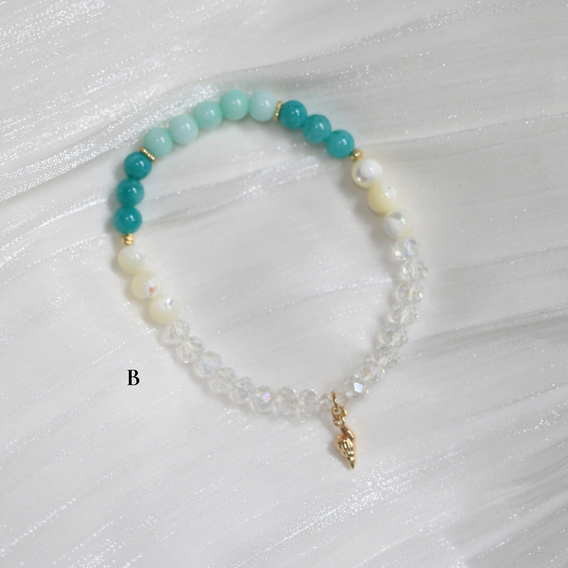 Beaded bracelet with turquoise, white, and gold beads on a light gray background