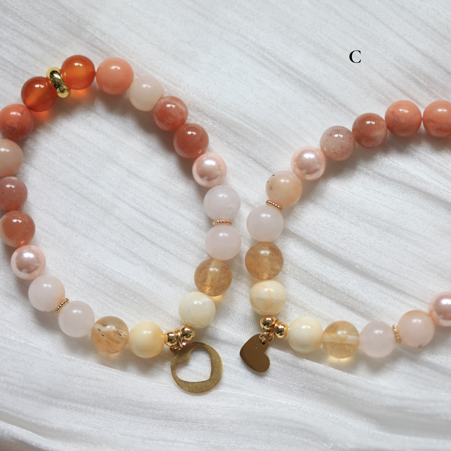 Matching Friendship Beaded bracelet with gold charms on a textured white surface