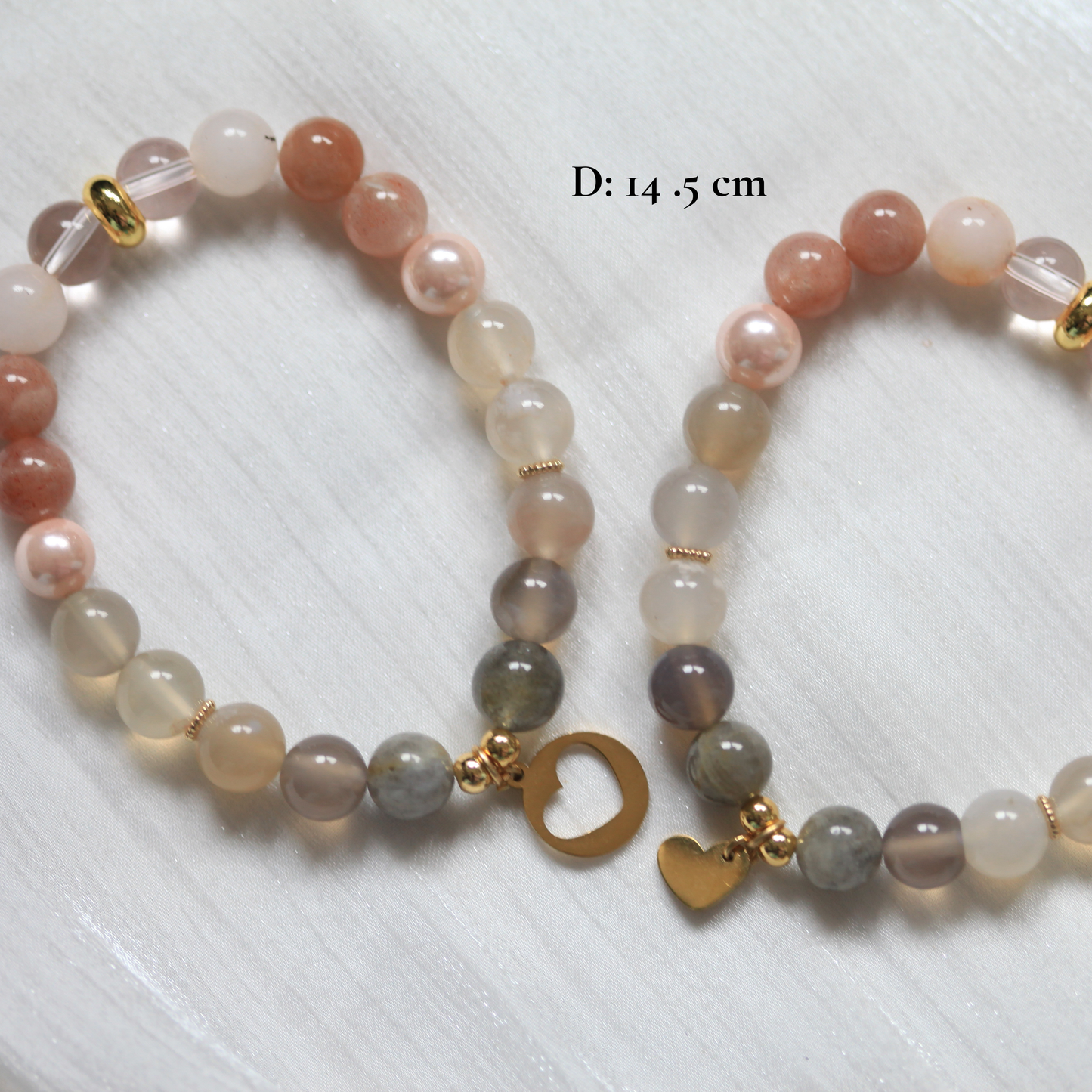 Two beaded bracelets with gold heart charms on a white background