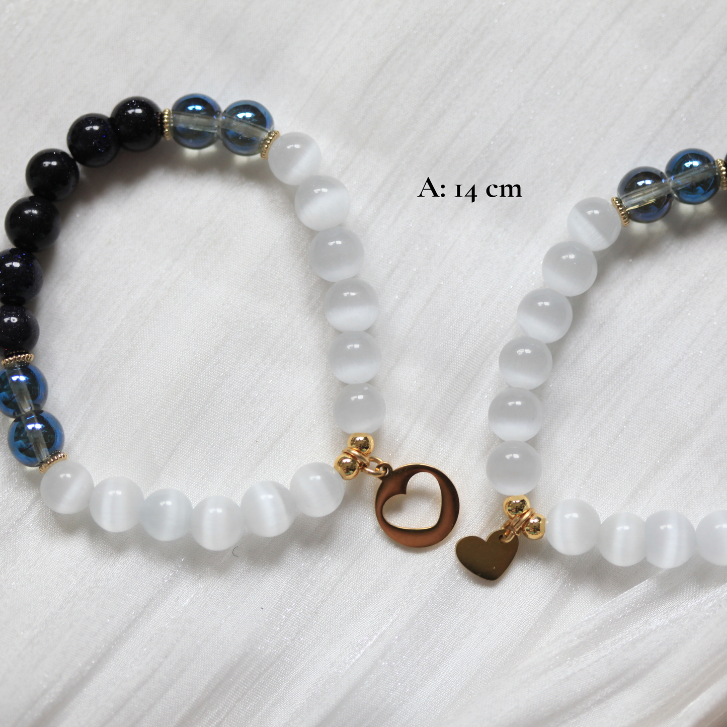 Two beaded matching friendship bracelets with charms on a white fabric background