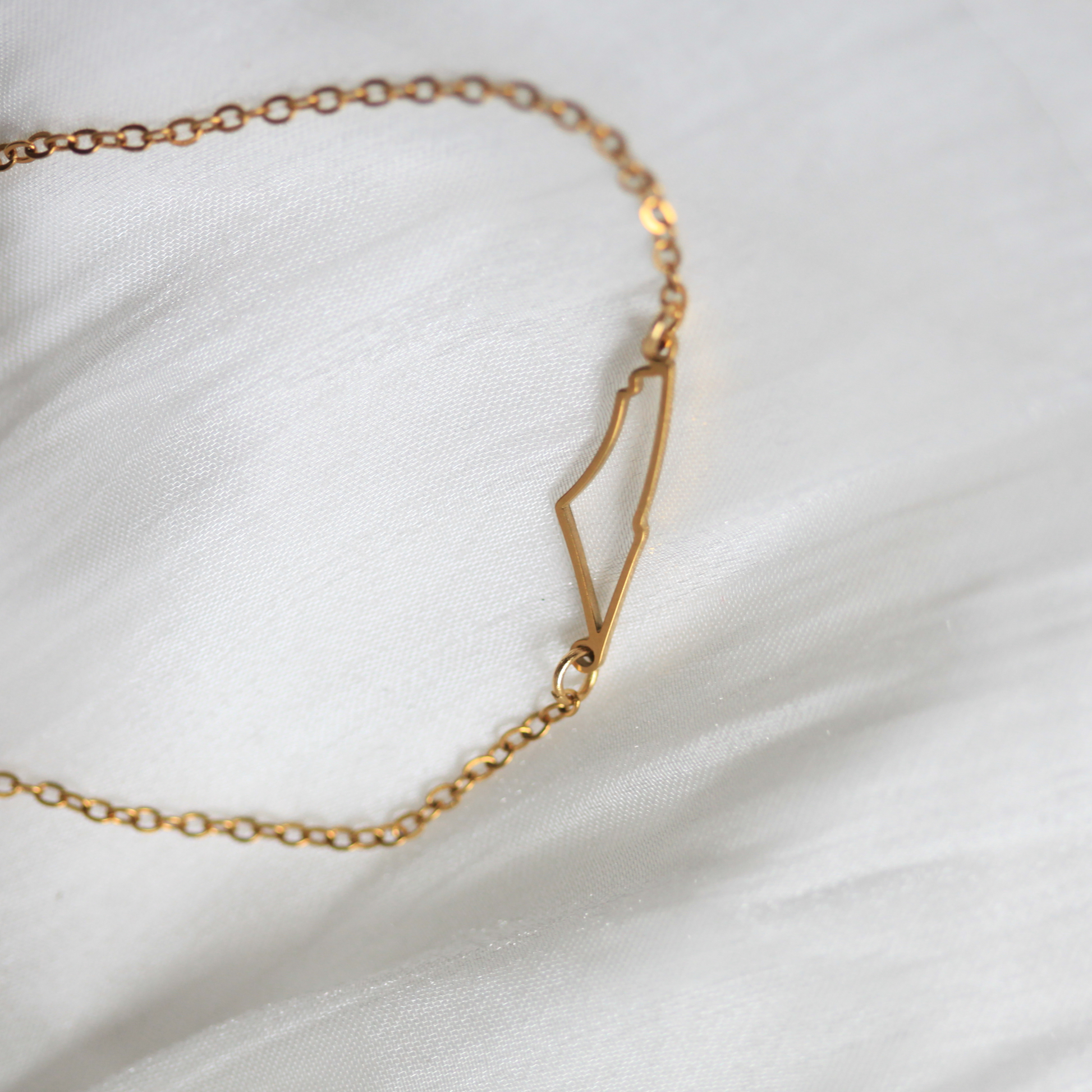 Gold chain palestine bracelet on a white fabric background