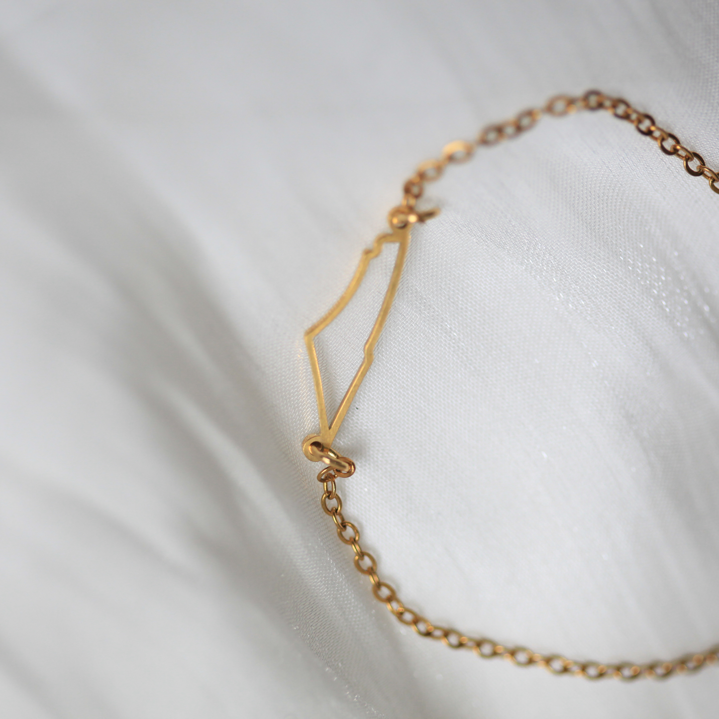 Gold bracelet on a white fabric background