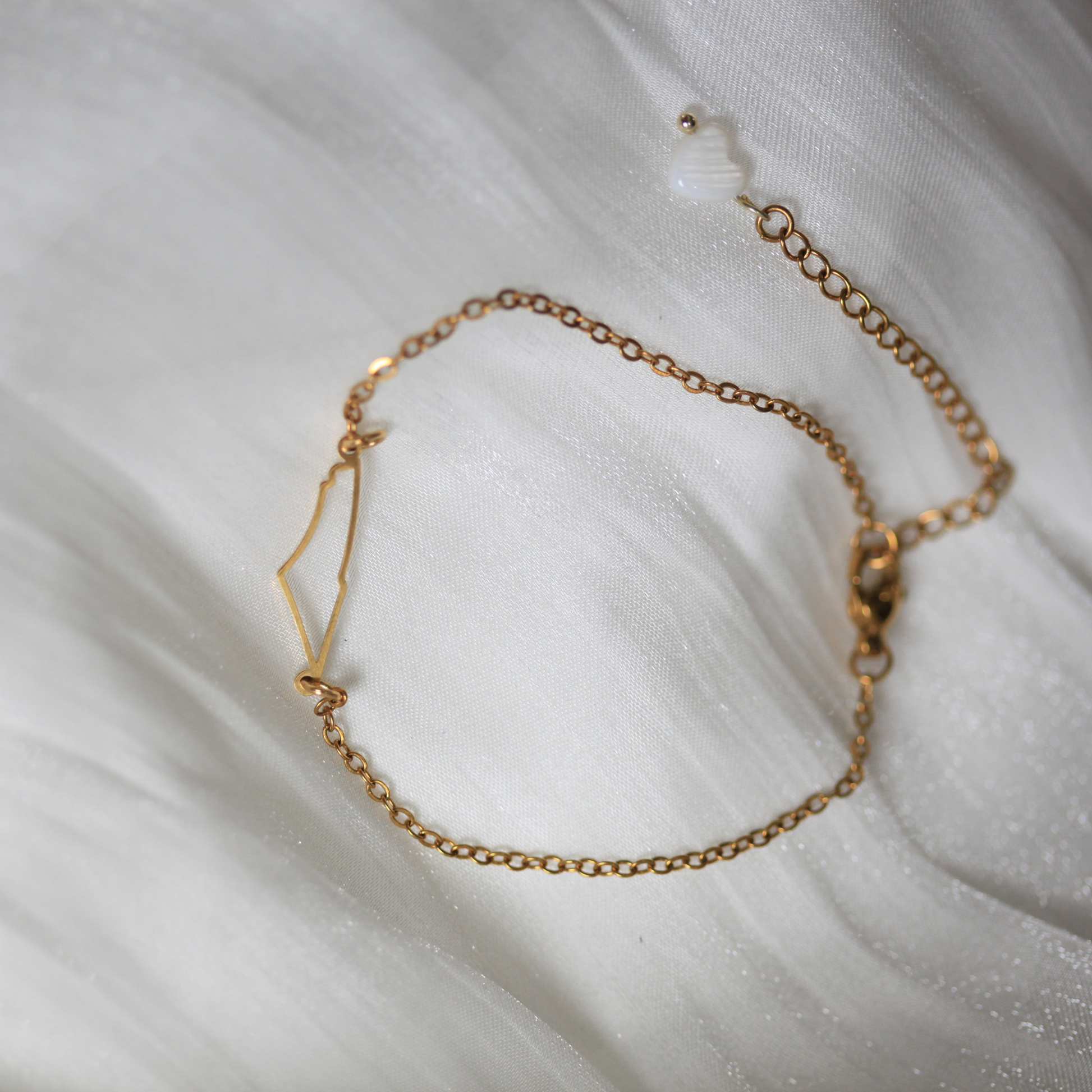 Gold chain bracelet on a white fabric background