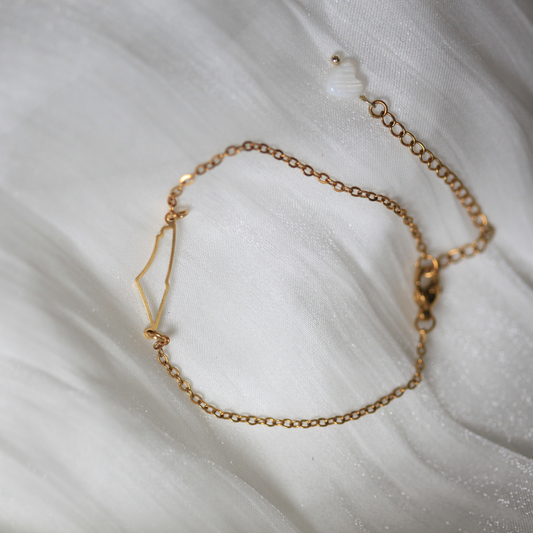 Gold chain bracelet on a white fabric background