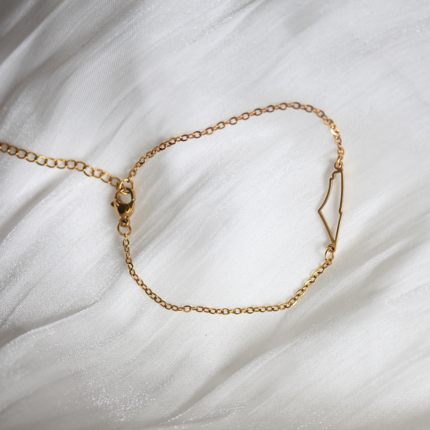 Gold chain bracelet on a white fabric background. Made by Dreamers' Side