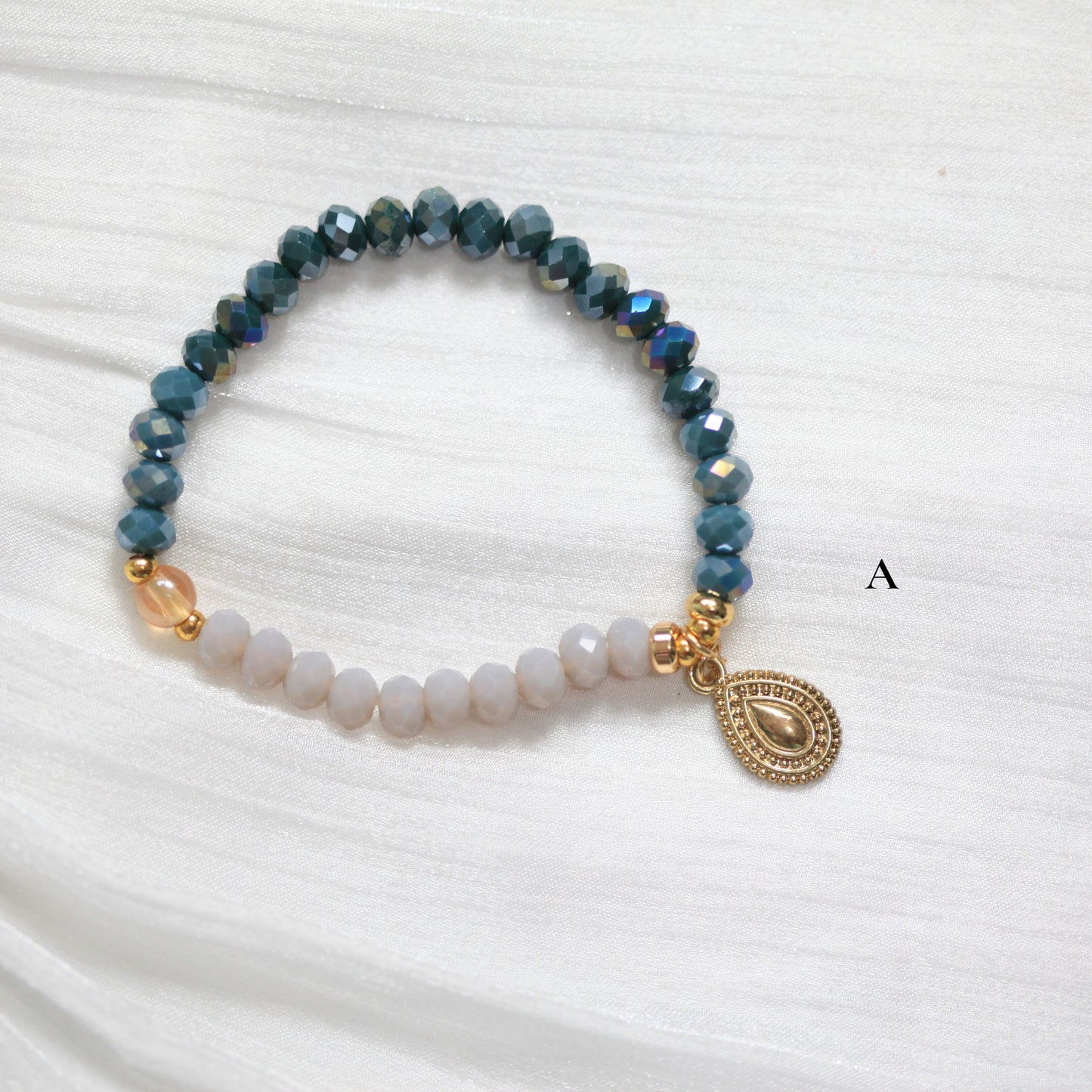 Tasbih Beaded bracelet with a gold charm on a white fabric 