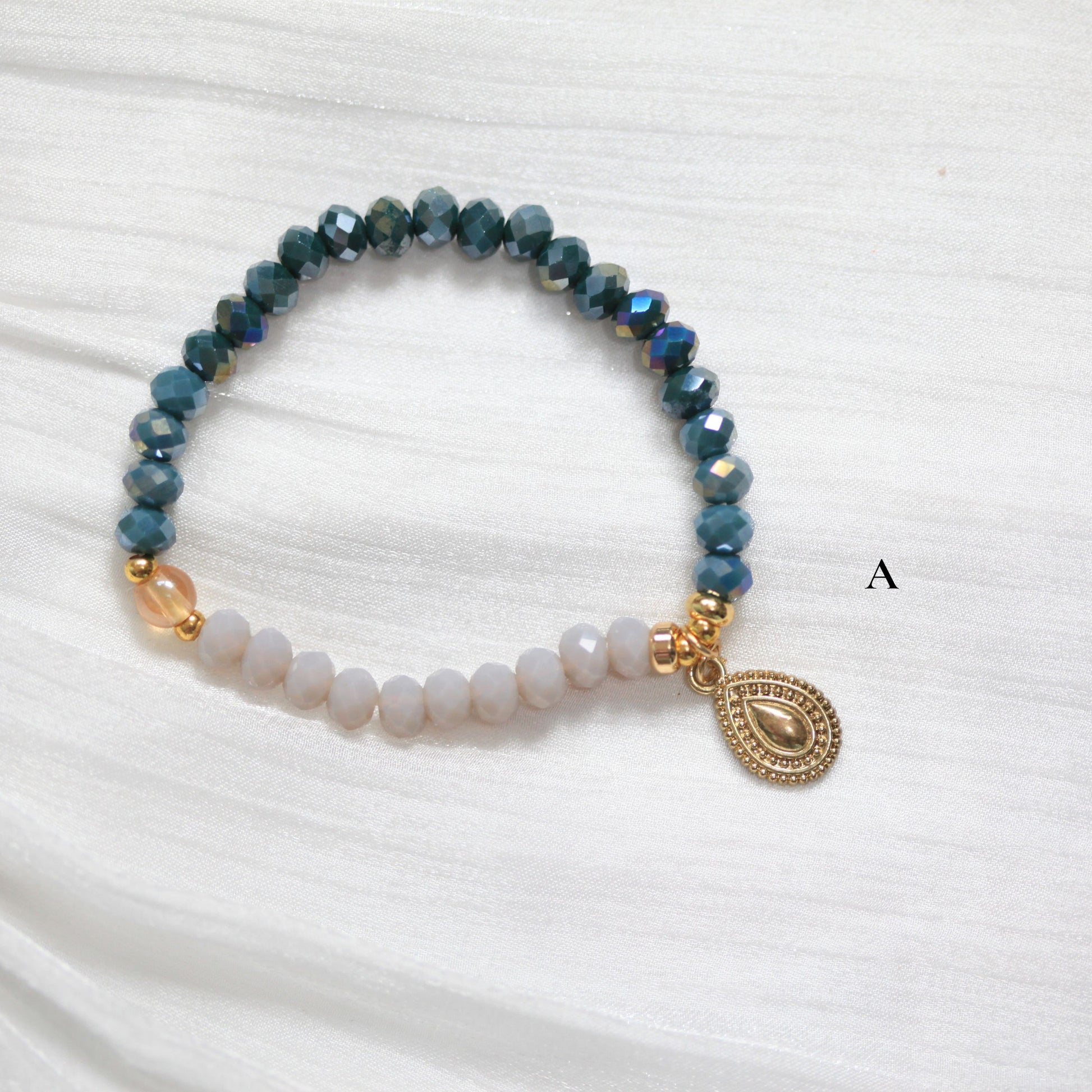 Tasbih Beaded bracelet with a gold charm on a white fabric 