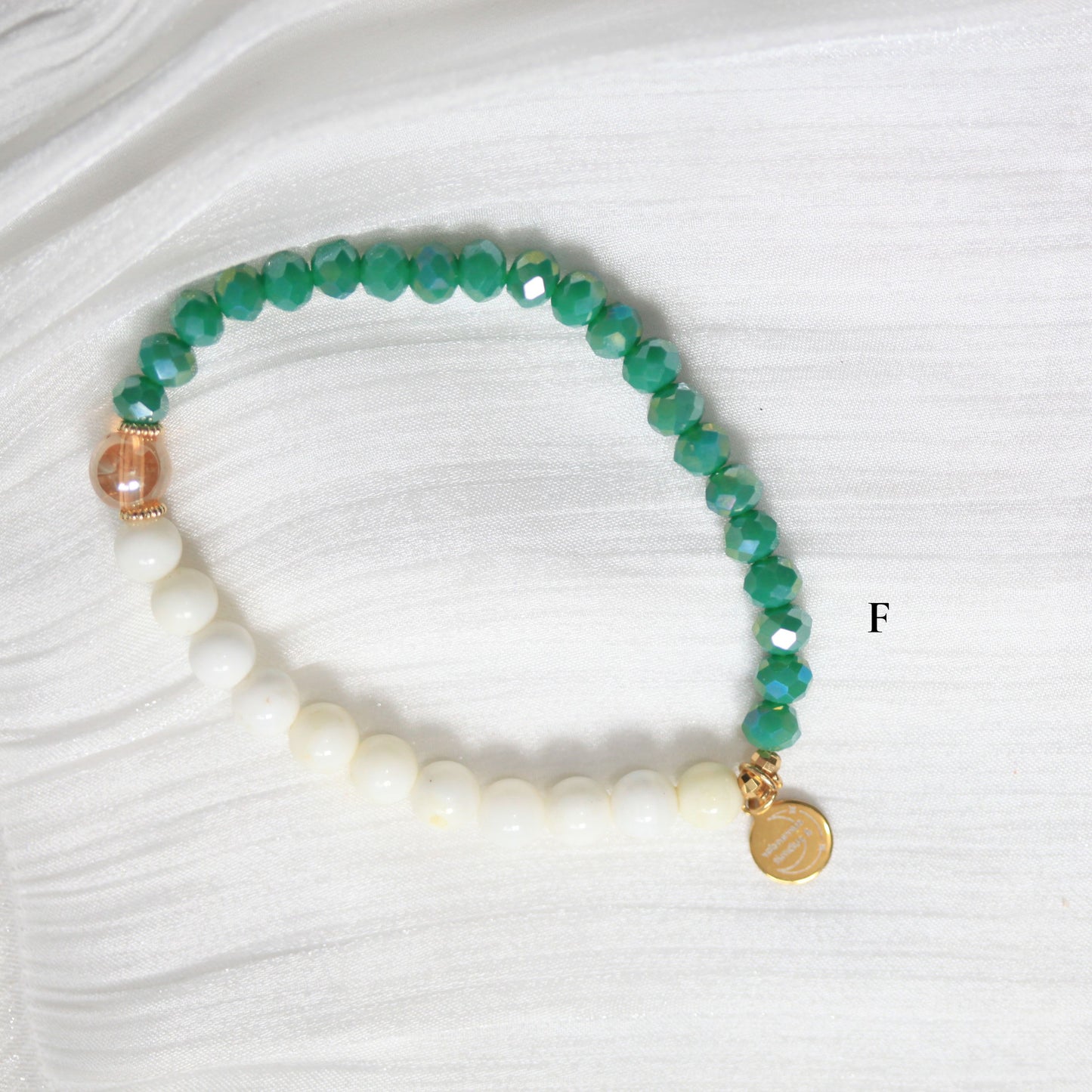 Beaded bracelet with green, white, and gold beads on a white background