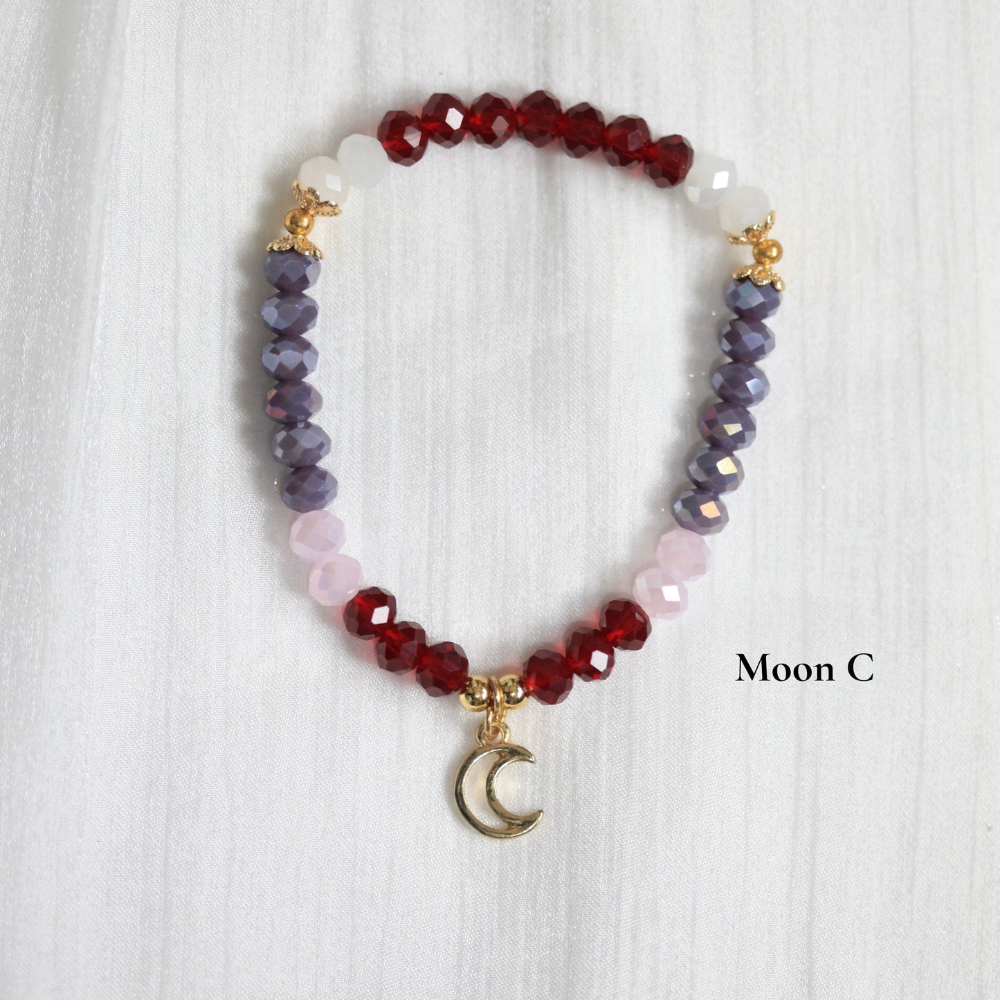 Beaded tasbih bracelet with a moon charm on a white background, branded 'Moon C'.