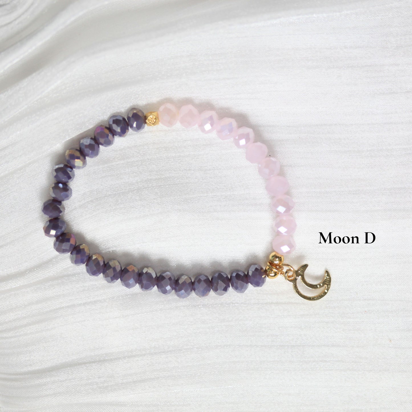 Beaded tasbih bracelet with a gold charm on a white textured background, branded 'Moon D'.