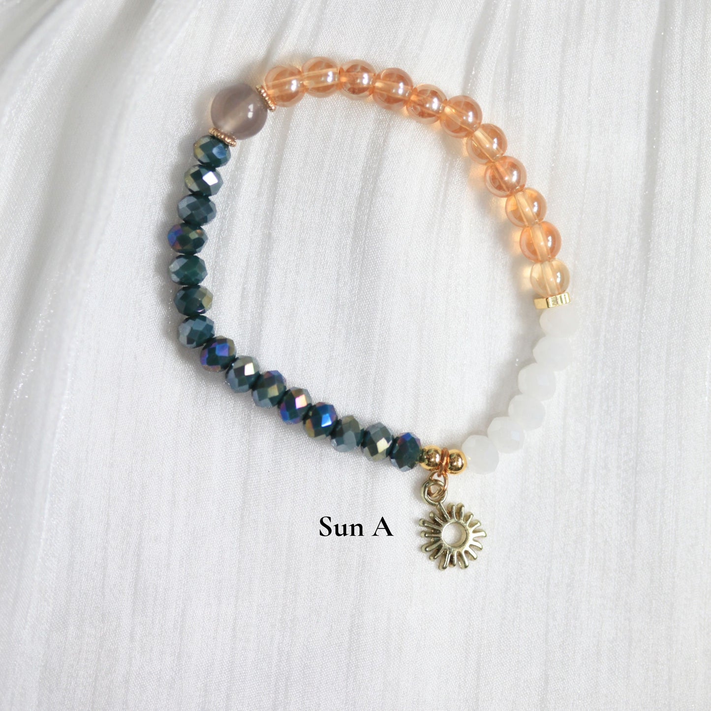 Beaded tasbihbracelet with a sun charm on a white fabric background 