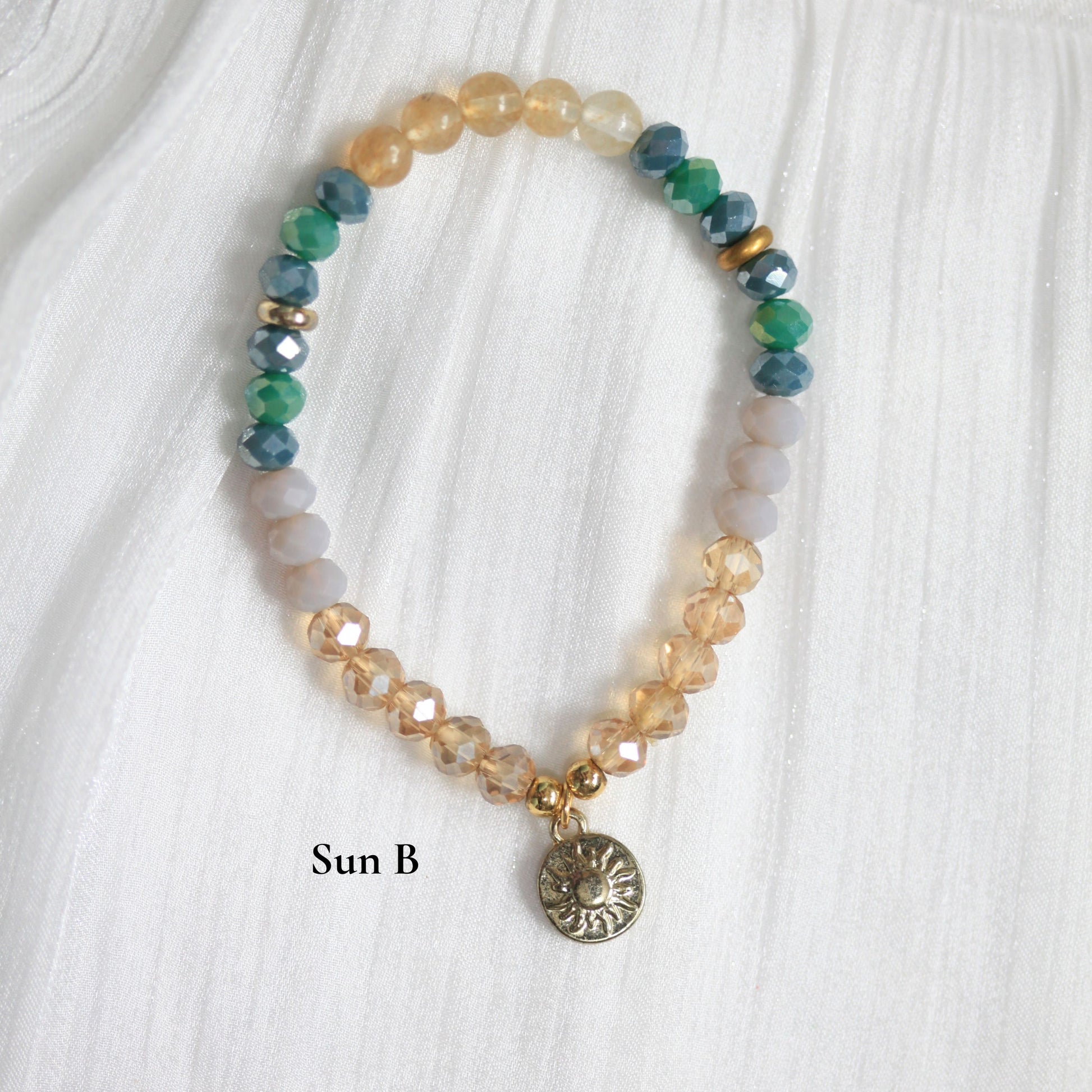 Dreamers' Side Beaded tasbih bracelet with a sun charm on a white fabric background