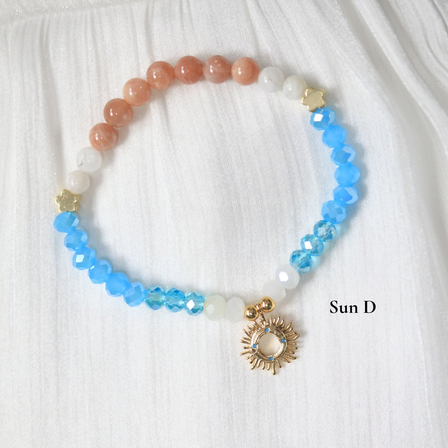 Beaded tasbih bracelet with sun charm on a white fabric background