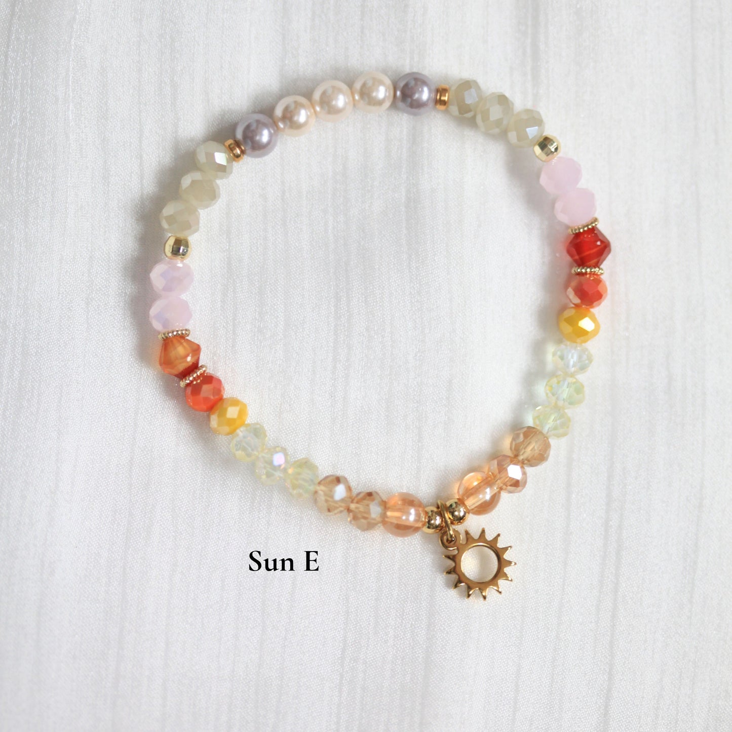Multicolored tasbih beaded bracelet with a sun charm on a white background