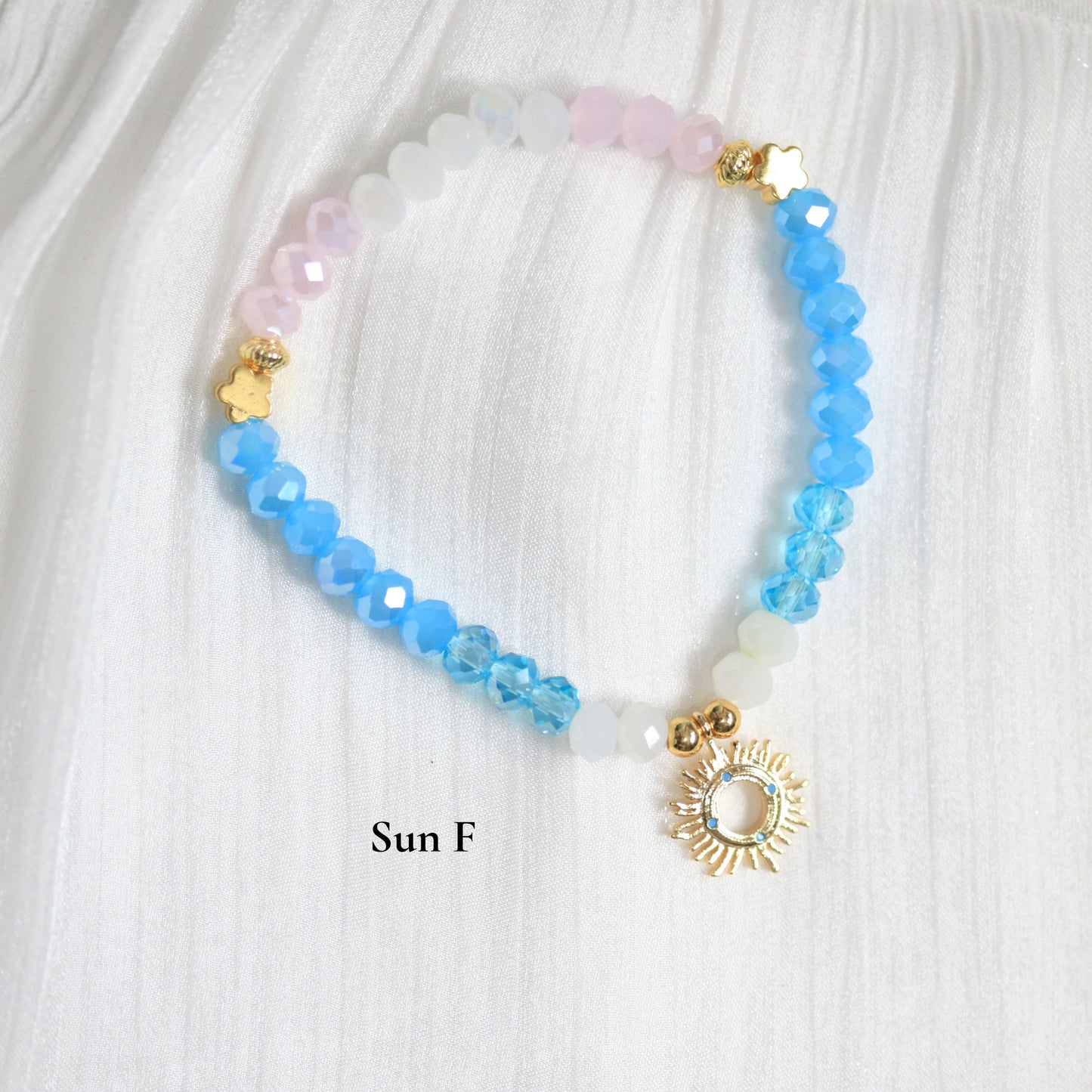 Beaded tasbih bracelet with a sun charm on a white fabric background