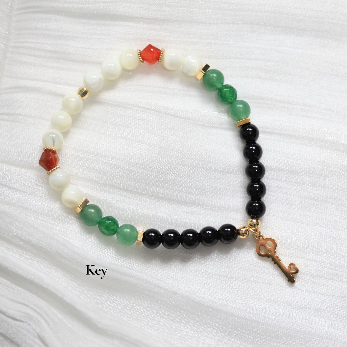 Beaded bracelet with a key charm on a white background