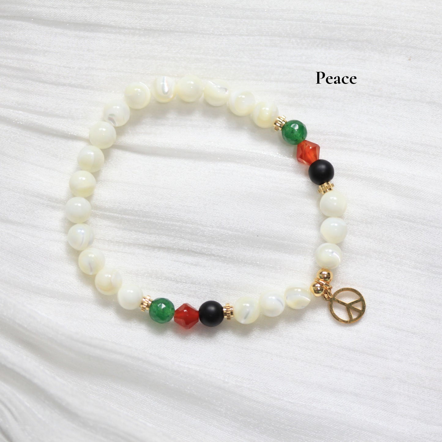 Beaded bracelet with peace charm on a white fabric background