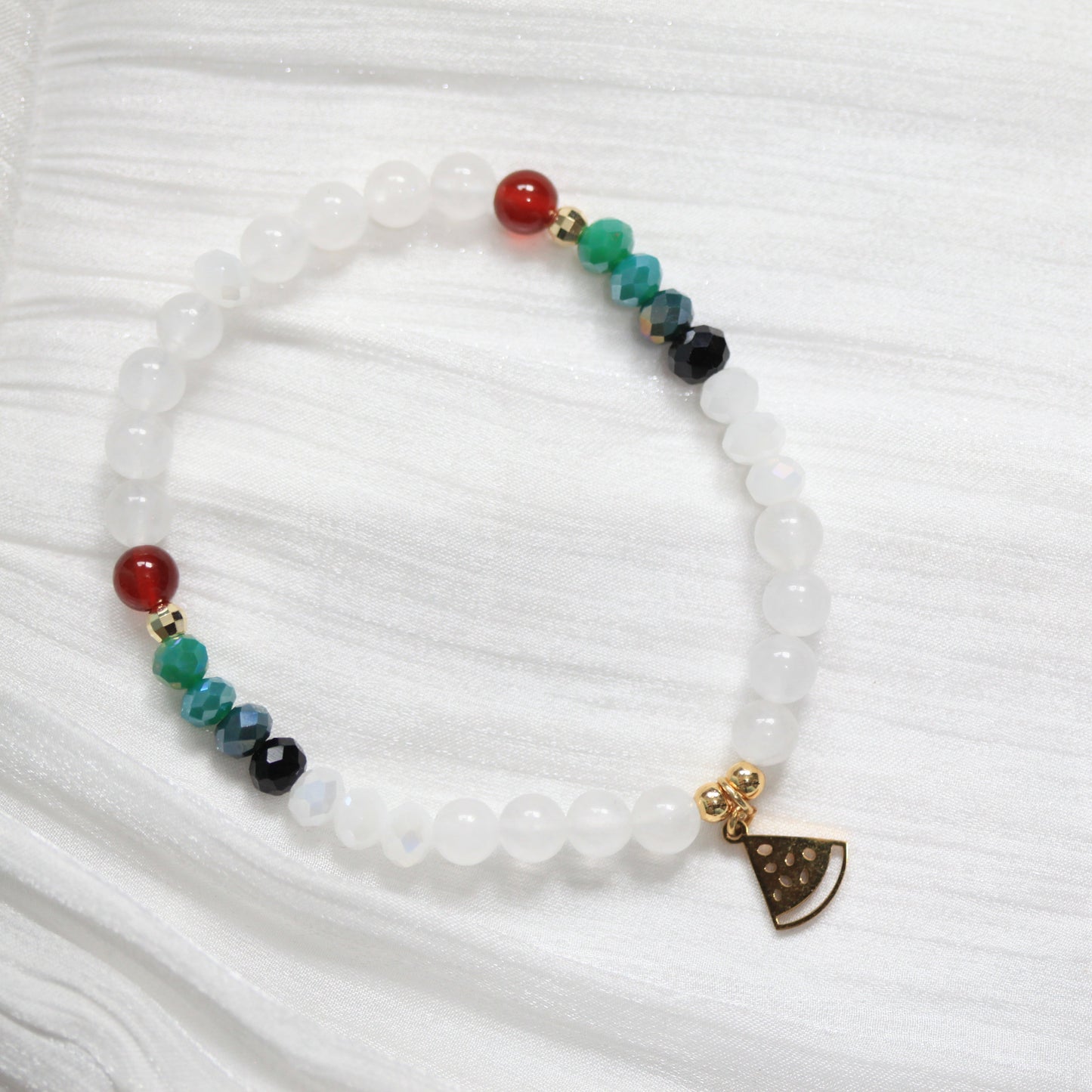 Tasbih Bracelet with colorful beads and a watermelon small charm on a white fabric background