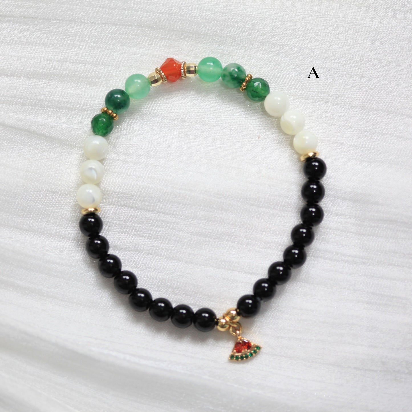 Tasbih Bracelet with colorful beads and a watermelon small charm on a white fabric background