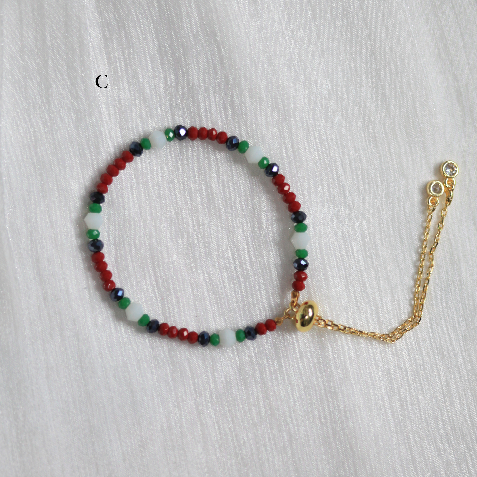 Multicolored beaded bracelet with a gold chain on a light gray background