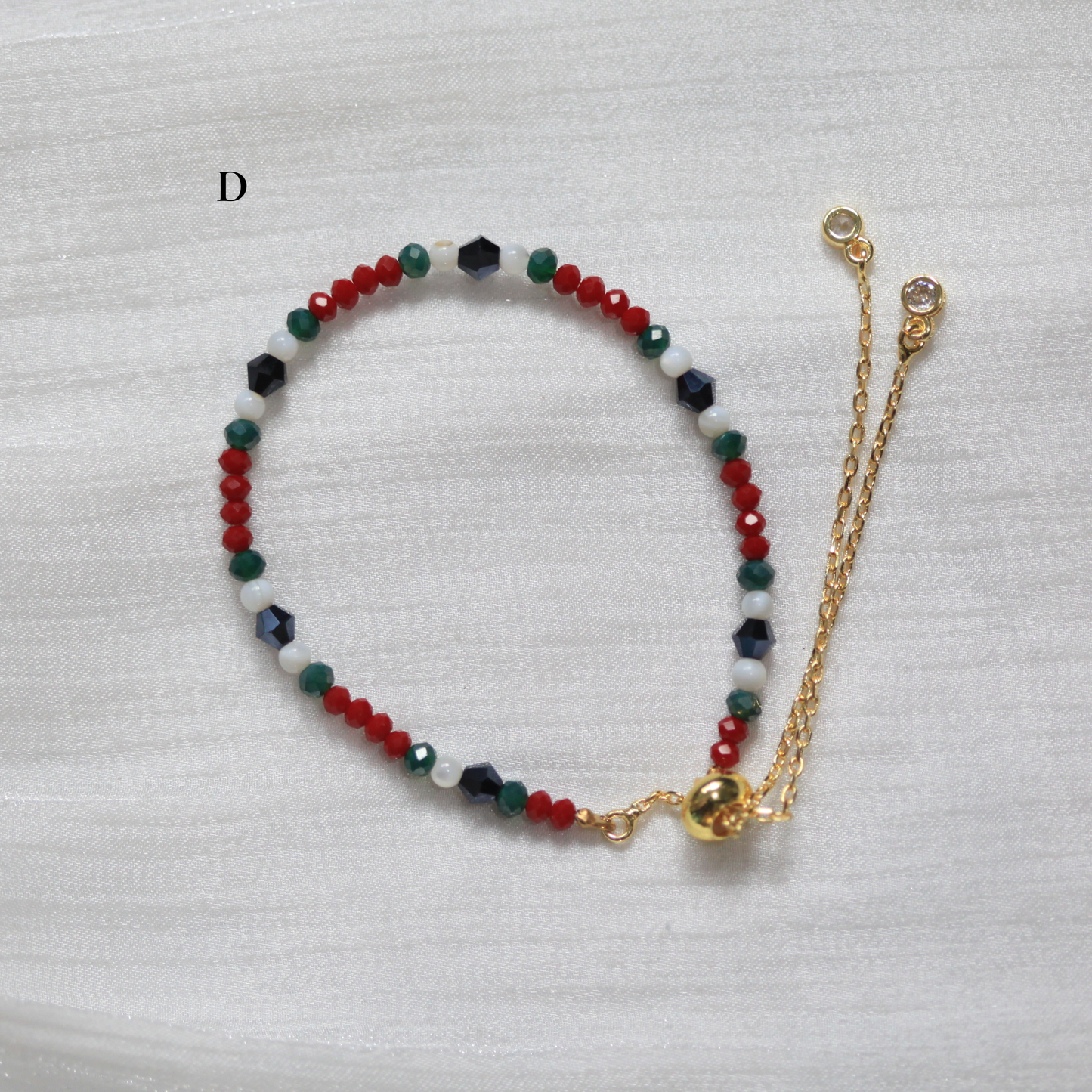 Multicolored beaded bracelet with a gold chain on a light gray background