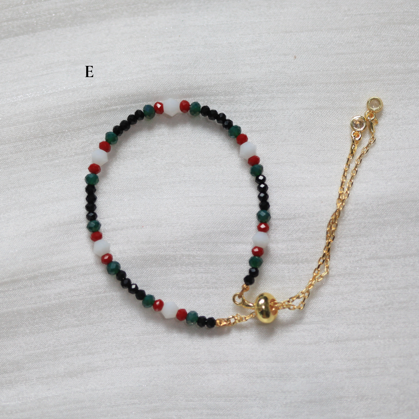 Multicolored beaded bracelet with a gold chain on a white background