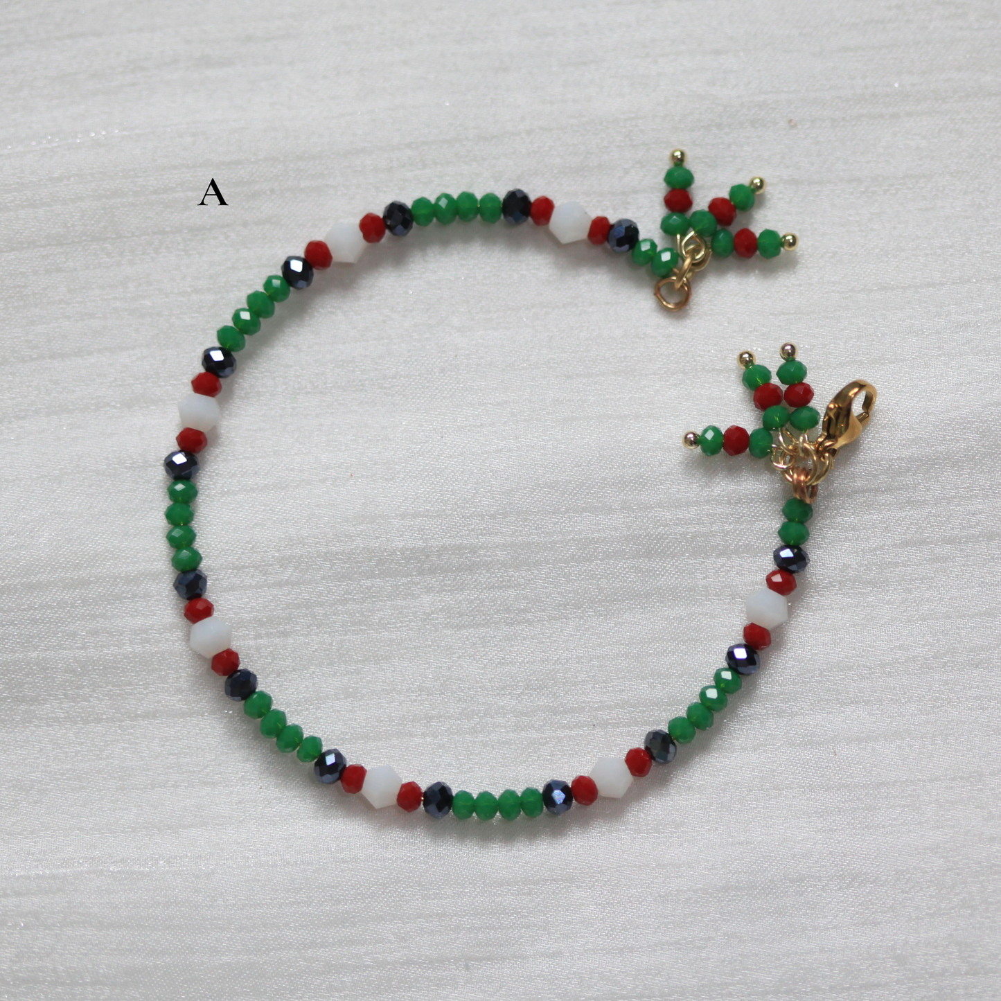 Beaded cuff bracelet with colorful beads and gold clasp on a white fabric background. Tatreez inspired.